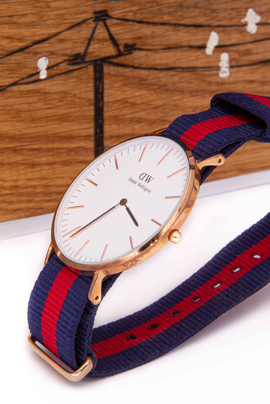 Daniel Wellington. Photo montre profil fond tableau en bois.